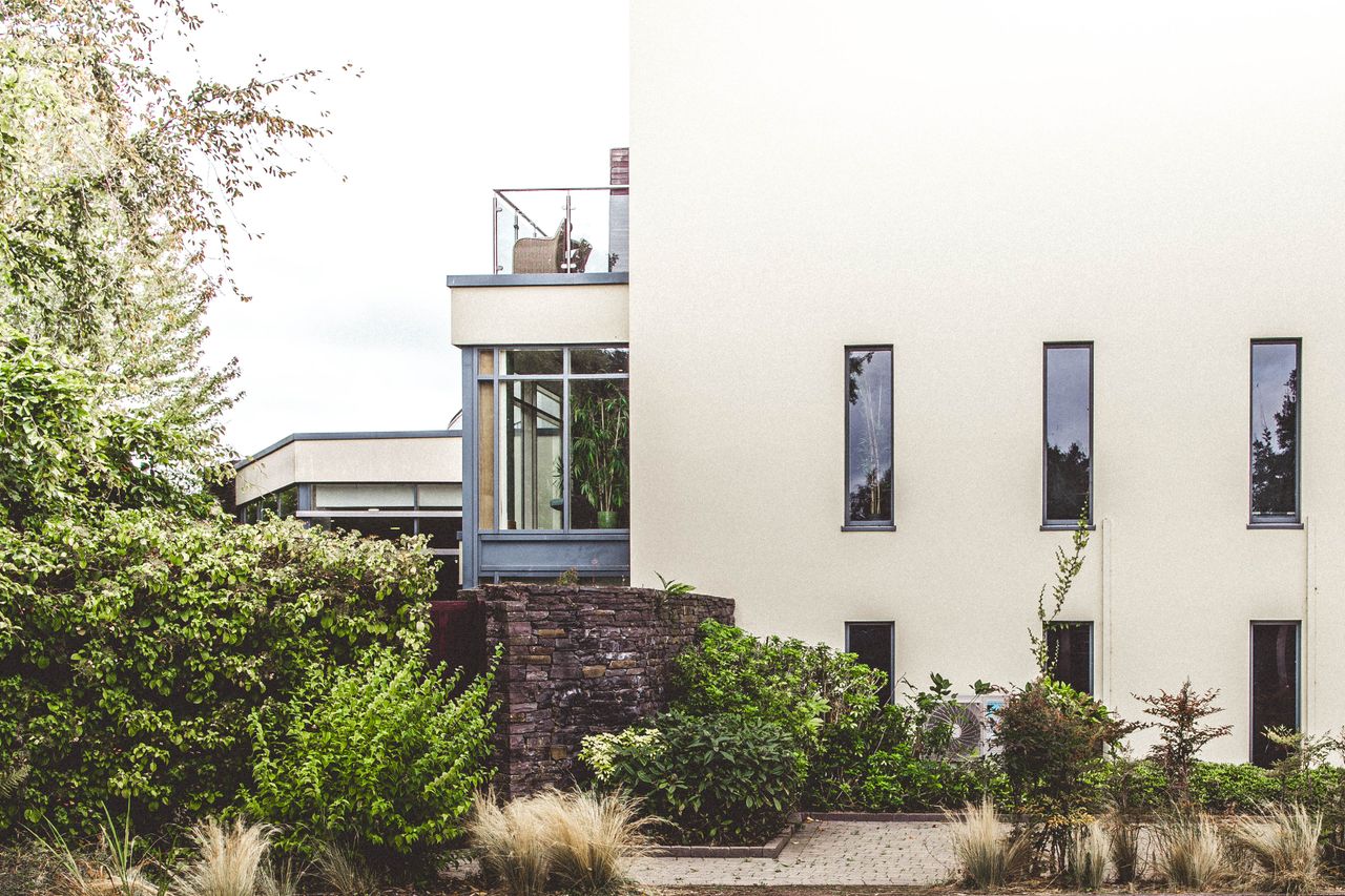 Elegant modern home exterior surrounded by lush greenery in Cork, Ireland.